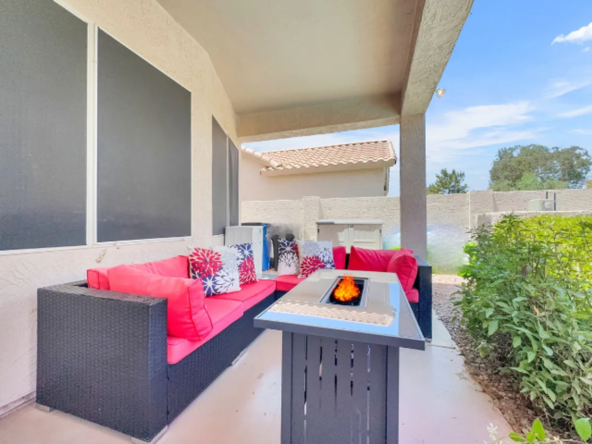 A cozy outdoor fire pit area with stylish red seating and decorative pillows, set up for socializing and evening relaxation. The space is designed for gathering around the fire, suggesting comfort and memorable moments under the open sky.