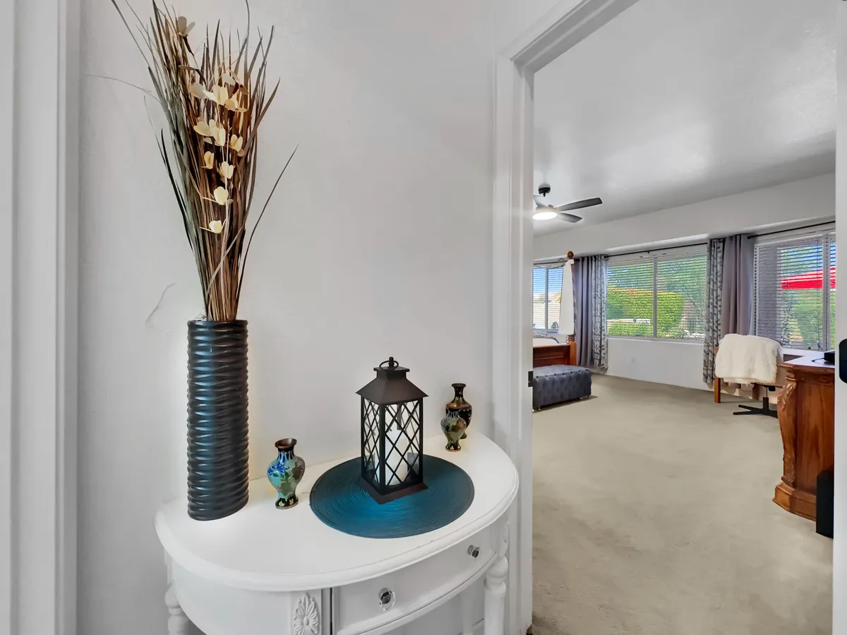 A round table adorned with a floral arrangement, a decorative lantern, and colorful vases, positioned in a welcoming entry or gathering area. The overall mood is warm and inviting, emphasizing a sense of arrival and personalized care.